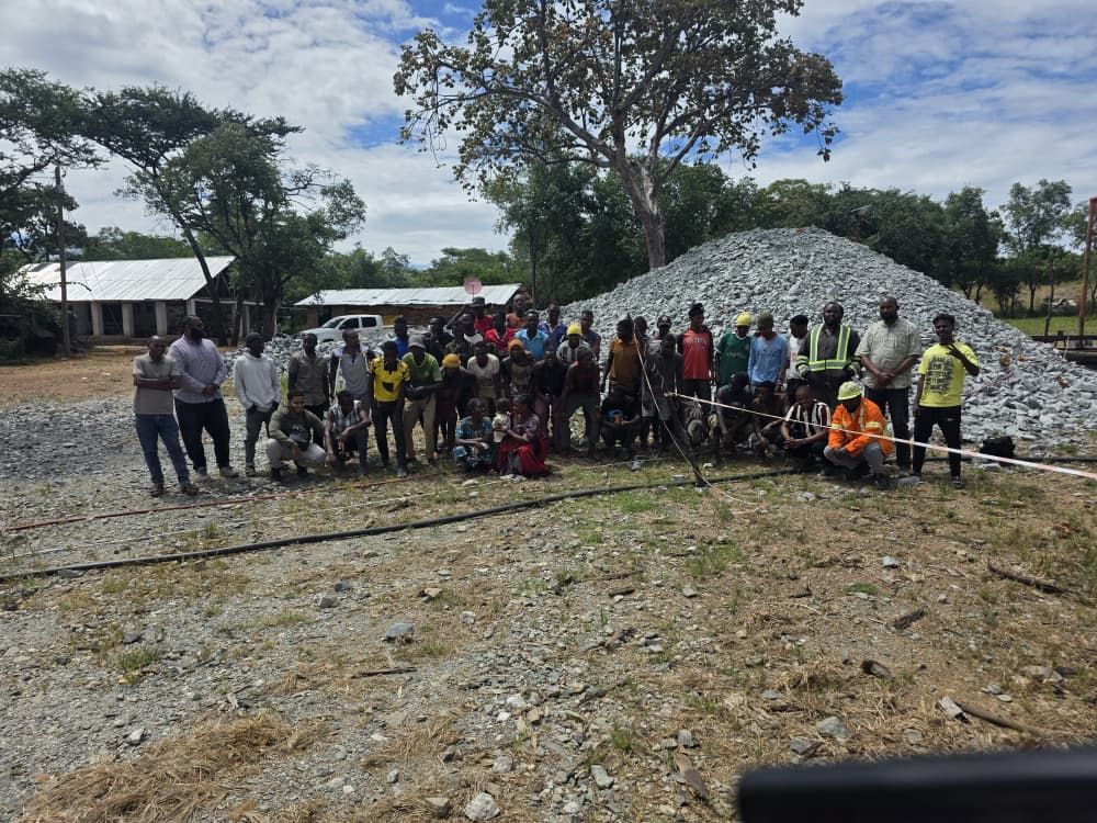 Afriglobal site team in front of an ore stockpile at the Chunya site